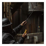 Wearing a hard hat and safety jacket, an individual inspects an industrial duct in a dimly lit setting using the WatchGas Fixed Carbon Fiber Probe with Teflon Insert from WatchGas to meticulously examine the area for gas detection.
