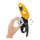 A hand assembles the Petzl RIG Compact Descender D021_ _00, revealing internal metal components and screws, and highlighting the AUTO-LOCK system. The yellow and black device by Petzl is shown against a white background.