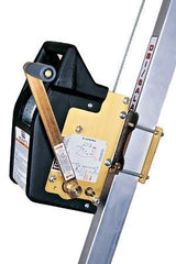 A close-up of the 3M DBI-SALA Fall Protection Salalift II Confined Space Retrieval Winch attached to a vertical metal rail. The device features a black casing with a golden metal plate and labels on the side. A galvanized steel cable runs through the system, indicating it's part of a safety or lifting mechanism.