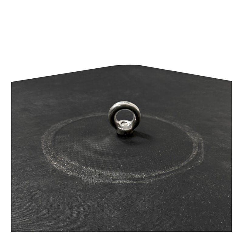 A close-up of the Frontline Fall Protection EcoAnchor Counterweight Fall Arrest Anchor System fixed on a black surface with a metallic ring at the center and a faint circular mark, set against a plain white background.