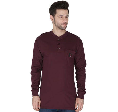 A man wearing a ForgeFR Forge FR Henley (MFRHNLY-004) in maroon, featuring long sleeves, buttons at the neck, and a chest pocket, designed to meet NFPA 2112 standards, stands against a white background.