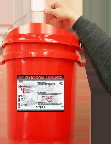 A person holds a red plastic bucket labeled "French Creek Production RHLD Synthetic Rope Horizontal Lifeline System," which features illustrations and specifications of essential fall protection safety equipment.