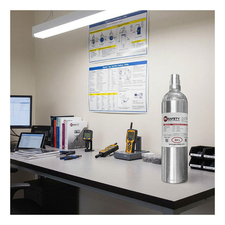 A PK Safety RKI Equivalent 4 Gas Calibration Gas Mix 34 Liter cylinder sits on a modern office desk with manuals, devices, and safety posters—ideal for storing calibration gas or performing bump test checks to RKI standards.