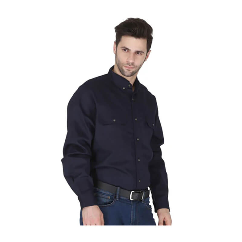 A man with short dark hair wears the ForgeFR Forge FR Solid Button Shirt MFRLB2PS024 and blue jeans, standing slightly to the side against a white background. This flame resistant shirt meets NFPA 2112 standards.