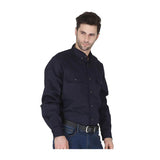A man with short dark hair wears the ForgeFR Forge FR Solid Button Shirt MFRLB2PS024 and blue jeans, standing slightly to the side against a white background. This flame resistant shirt meets NFPA 2112 standards.