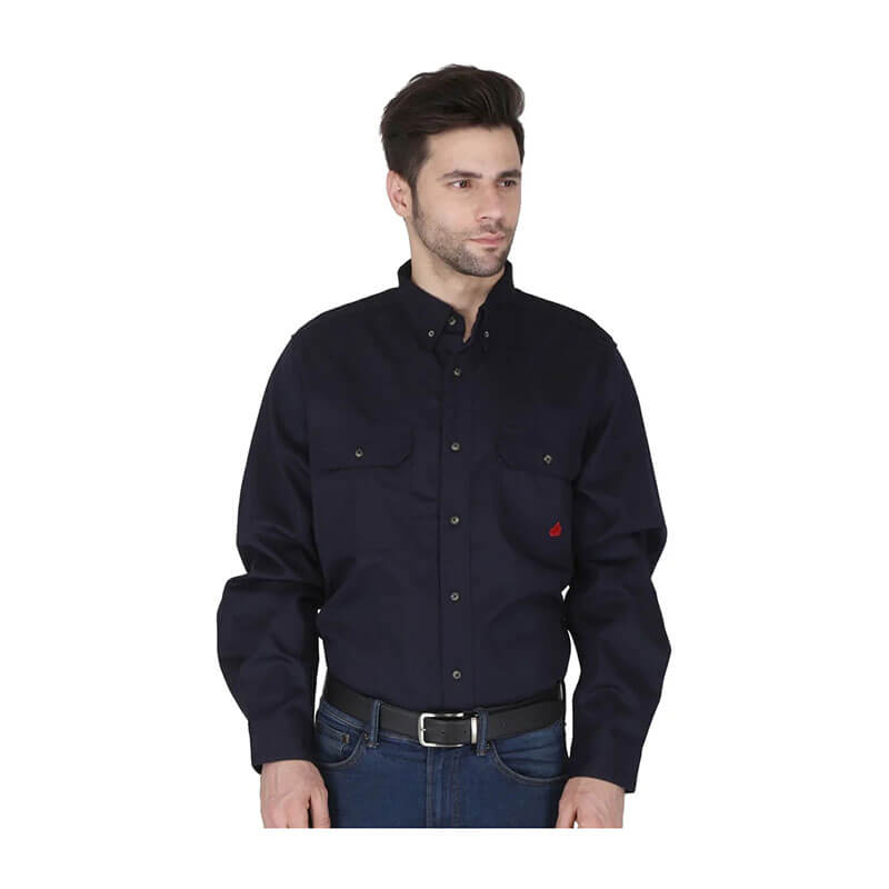 A man in a dark navy ForgeFR Forge FR Solid Button Shirt MFRLB2PS024 with chest pockets and blue jeans stands turned slightly, looking left. The FR shirt meets NFPA 2112 flame resistant clothing standards.