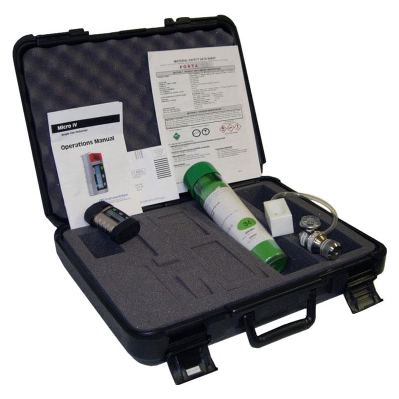 Open black carrying case with foam padding, containing an operations manual, a green and white cylinder, and a regulator for automatic calibration. Various small components indicate it's part of the GfG Micro IV O2 Single Gas Detector 1418-022 kit. The items come with a lifetime warranty.