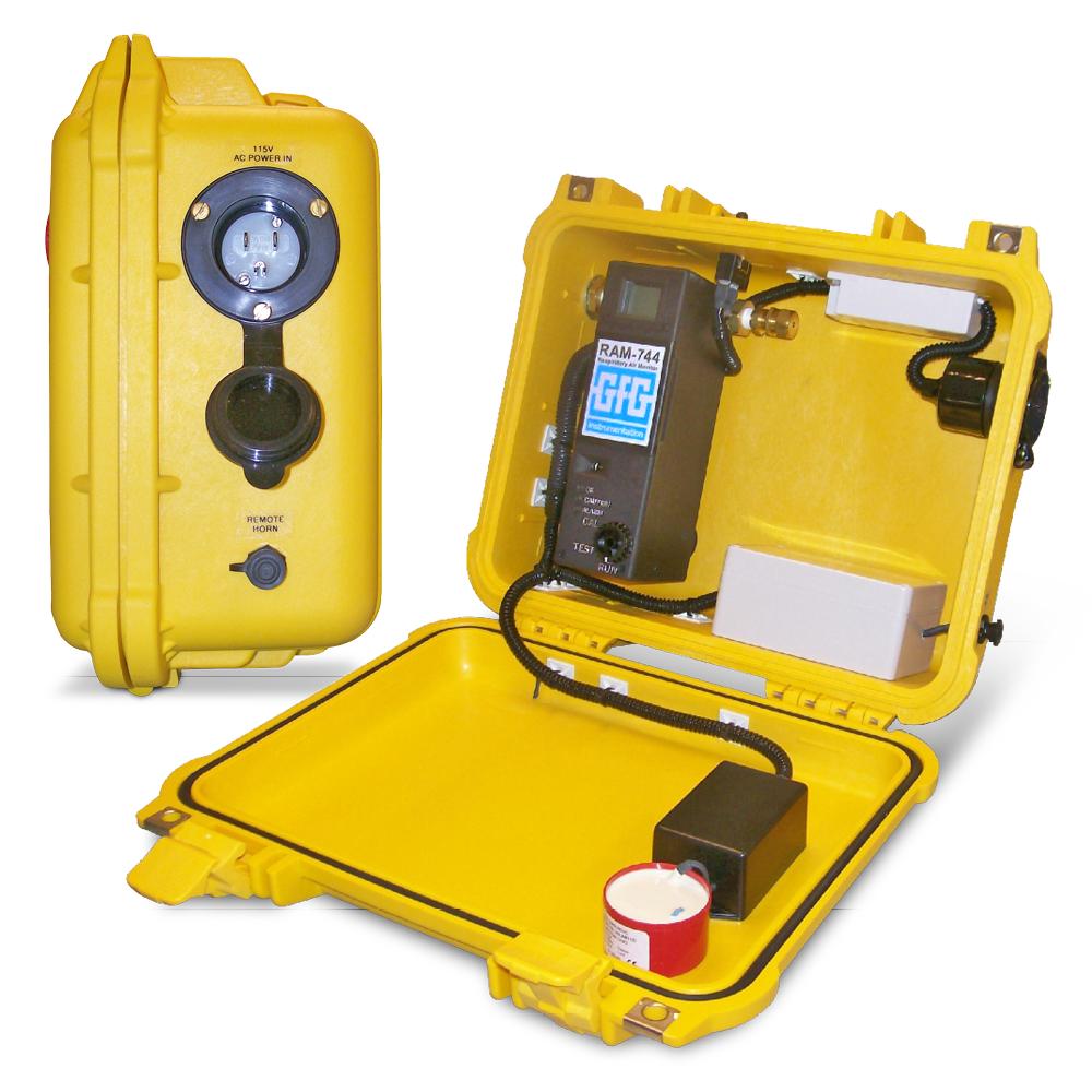 An open yellow case housing the GfG In-Line CO Monitor RAM 744 reveals equipment including a sensor and digital display for carbon monoxide monitoring. Next to it, a closed GfG case features an exterior with a pressure gauge and connection points designed for portable applications.