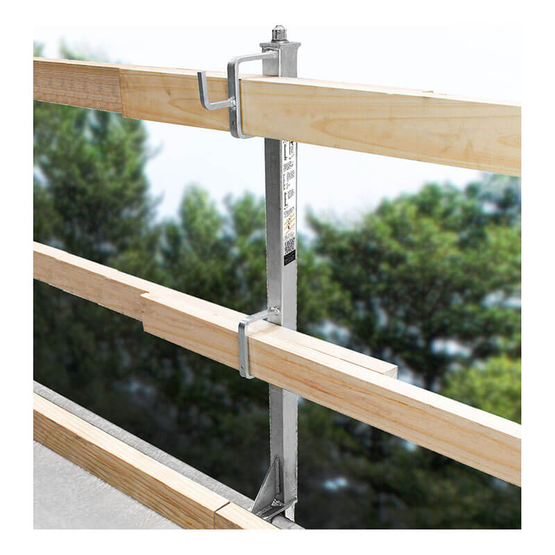 The Frontline Concrete Slab Grabber GUC2X4 by Frontline Fall Protection supports two horizontal wooden beams with metal clamps for perimeter edge protection, installed on a building edge, with green trees blurred in the background.