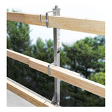 The Frontline Concrete Slab Grabber GUC2X4 by Frontline Fall Protection supports two horizontal wooden beams with metal clamps for perimeter edge protection, installed on a building edge, with green trees blurred in the background.