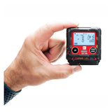 A hand holds the RKI Instruments GX-3R 4 Gas Confined Space Monitor 72-RA-C, a compact black device with "Air" and "Power Mode" buttons and a digital display for gas readings, ideal for confined space safety checks.