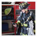 A firefighter in full gear stands beside a fire truck, holding a radio and smiling. The truck’s open compartment displays equipment bags and an RKI Instruments GX-6100 4-Gas Monitor w/TC Sensor (72-61AXXT-C) inside.
