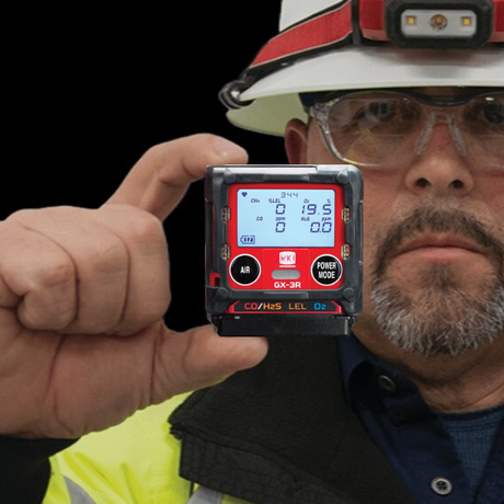 Person wearing safety gear holding a digital gas detector