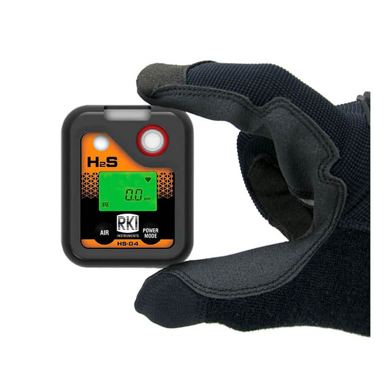 A gloved hand holds an RKI Instruments HS-04 Series H2S Single Gas Monitor 73-0063, a compact black and orange device with a digital display reading "0.0 ppm," labeled "H2S" by RKI Instruments.