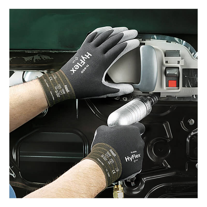 Wearing Ansell HyFlex Polyurethane Coated Glove 11-600 by Ansell, which features a durable polyurethane coating and a comfortable nylon knit liner, an individual uses a power tool to assemble or repair the interior panel of a car door.