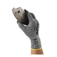An individual wearing an Ansell HyFlex Nitrile Foam Glove 11-801 from Ansell, distinguished by its gray design and foam nitrile coating, holds a rusty, jagged piece of metal against a white background.