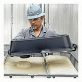 A man in safety gear places an UltraTech IBC Mini Funnel 0649 onto an industrial container inside a metal-walled facility.