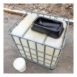 An UltraTech IBC Mini Funnel 0649 is placed on a large white plastic IBC container with a metal cage. A black rectangular basin sits on top, a white bucket is beside it, and dirt can be seen in the background.
