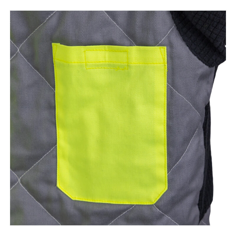 A close-up of quilted gray fabric displays a bright yellow square pocket with visible stitching, highlighting the detailed craftsmanship of the NSA DRIFIRE FR Hi-Vis Insulated Jacket JKT-01C3-HV.