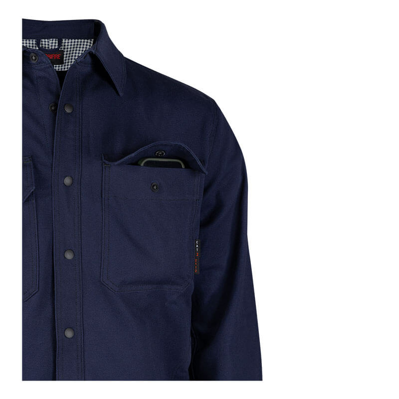 The NSA DRIFIRE FR Range Flex Shirt Jacket JKT-6B in navy blue, featuring a checkered inner lining, is shown from the chest up with a smartphone partially visible in the left chest pocket. This is a lightweight work jacket.