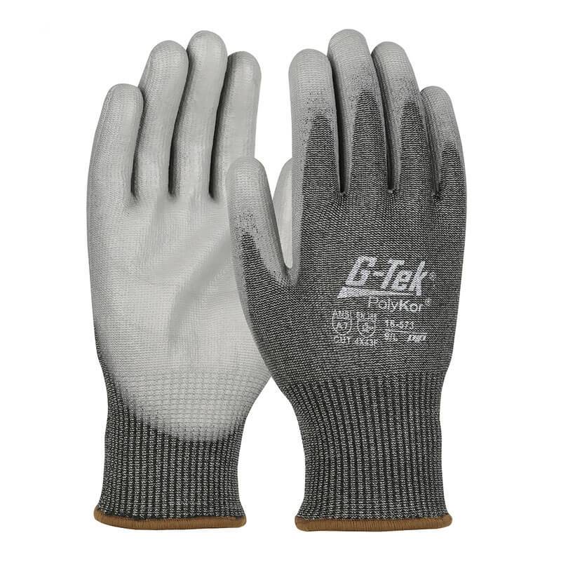 The PIP G-Tek PolyKor Glove with PU Coated Flat Grip (16-573) from Protective Industrial Products features a textured grip and a knit wrist cuff for a secure fit. These gray and white gloves are touchscreen-compatible and offer impressive cut resistance, ensuring both safety and convenience on the job.