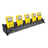 Five yellow BW Technologies by Honeywell GasAlert MicroClip detectors are docked in a row on the MC2-C01-MC5 5 Unit Cradle Charger, each featuring display screens and button controls while the charger is plugged in for easy charging.