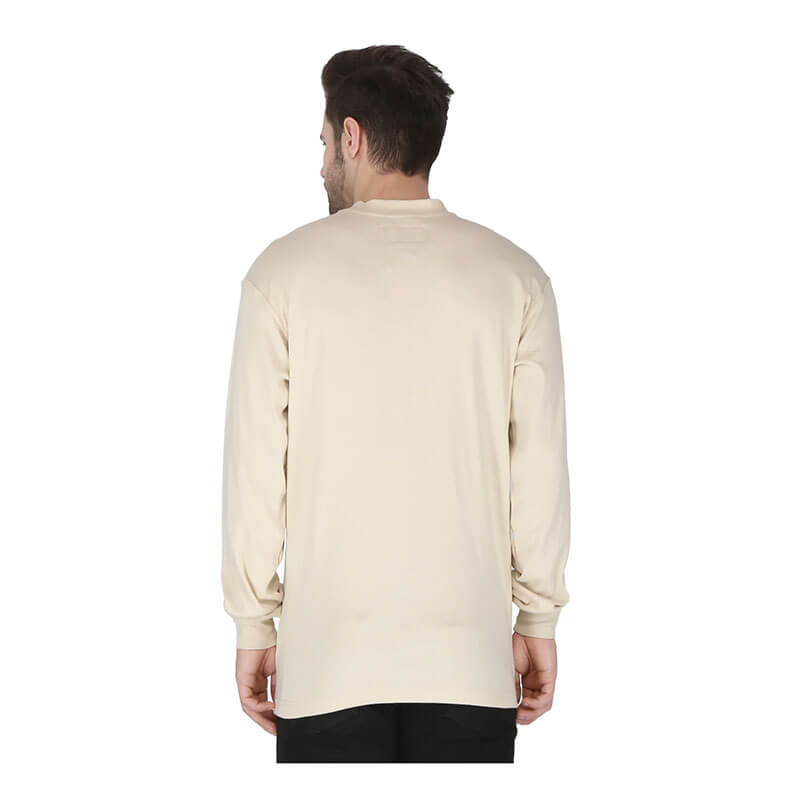 A man with short dark hair stands with his back to the camera, wearing a ForgeFR Forge FR Henley MFRHNLY-004 long-sleeved beige shirt and black pants against a plain white background.