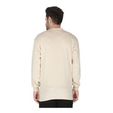 A man with short dark hair stands with his back to the camera, wearing a ForgeFR Forge FR Henley MFRHNLY-004 long-sleeved beige shirt and black pants against a plain white background.