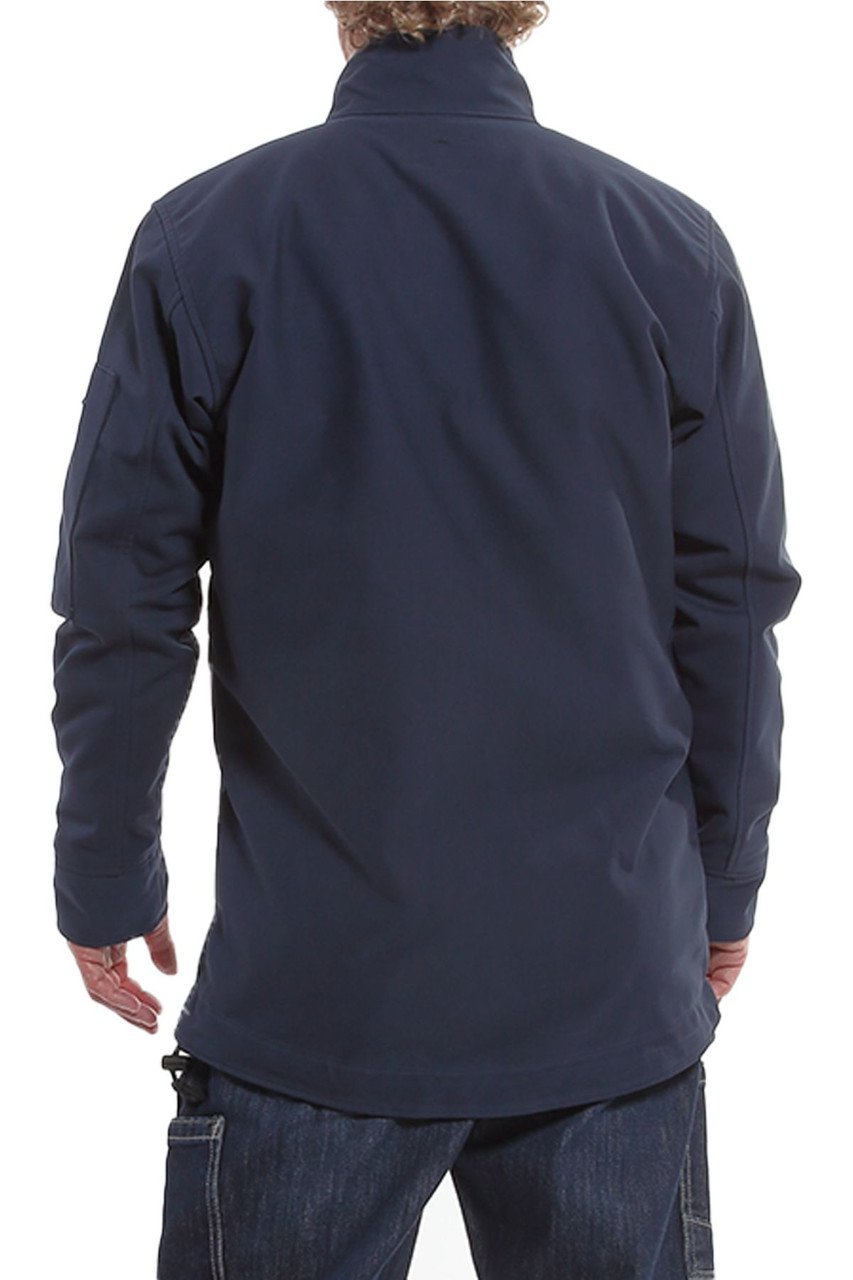 An individual is seen from the back, wearing the NSA DRIFIRE IA FR Windbreaker Jacket in navy blue, crafted from GORE PYRAD fabric. The jacket features a high collar and long sleeves, paired with dark jeans against a white background that complements its minimalist aesthetic.