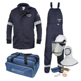 The protective gear set includes a navy NSA 12 Cal Enespro Arc Flash Jacket & Bib Overalls Kit EN12KTWUNB03_ _, along with a helmet featuring a face shield. Accessories consist of gloves, safety glasses, ear plugs, a hood, and a blue carrying bag with the "enespro" logo. The jacket complies with NFPA 70E safety standards.