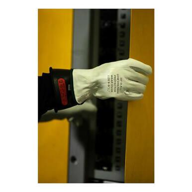 A person wearing a white safety glove with clear branding grips the edge of a yellow surface, demonstrating their electrically tested NSA Class 0 ArcGuard Rubber Voltage Glove Kit.