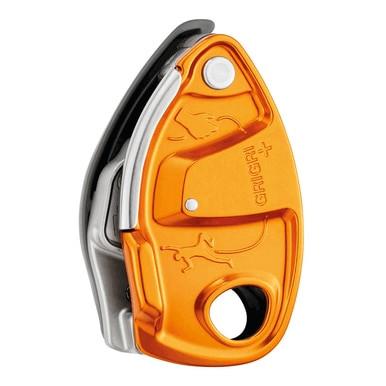 Detailed view of the Petzl GRIGRI + Belay Device D13A, showcasing its orange and silver metal body with a lever and attachment hole. The surface features the name "Petzl GRIGRI" along with a minimalist climber illustration. This model is equipped with an anti-panic handle for improved assisted braking performance.