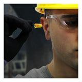 A person wearing a yellow hard hat and safety glasses uses a gloved hand to insert a PIP Pinchfit BioSoft Disposable Foam Ear Plug PF-1, highlighting the importance of hearing protection on the job.