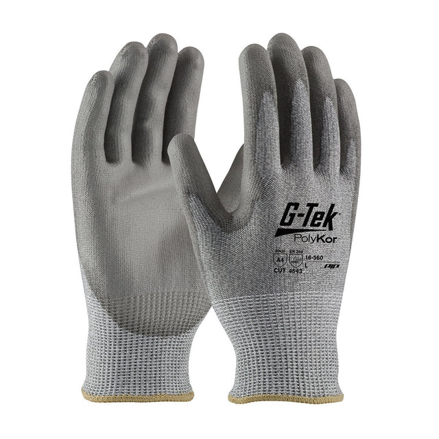 A pair of gray safety gloves, described as "PIP G-Tek PolyKor," displays black text and a logo on the back. These gloves, produced by PIP - Protective Industrial Products, include a polyurethane-coated grip designed for improved cut resistance and feature textured palms with one facing forward and the other backward.