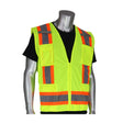 A mannequin showcases the PIP ANSI Class 2 Two-Tone Six-Pocket Surveyor's Vest from Protective Industrial Products, featuring reflective orange and gray stripes over a black shirt. This high-visibility garment comes with a zipper front and multiple pockets, offering both safety and functionality.