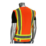 A mannequin is exhibiting a PIP Two-Tone Breakaway Surveyors Vest by PIP - Protective Industrial Products, styled in neon orange with reflective yellow and gray stripes over a black shirt. The vest is displayed from the back against a plain white backdrop.