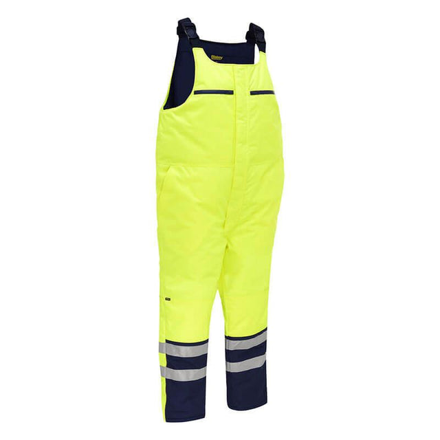 Introducing the PIP Bisley ANSI Class E Extreme Cold Bib Overall 318M6452T from Protective Industrial Products. These bright yellow overalls feature waterproof insulation and adjustable straps, with navy accents and reflective bands around the legs. Designed for visibility and protection in extreme cold, they are perfect for outdoor work environments.