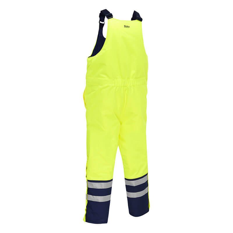 Introducing the PIP Bisley ANSI Class E Extreme Cold Bib Overall 318M6452T by Protective Industrial Products, these bib overalls come in a vibrant yellow with dark blue accents and reflective stripes on the legs. They are equipped with adjustable shoulder straps, waterproof insulation, and an elastic waistband to ensure safety in low-light conditions while providing excellent protection against extreme cold.