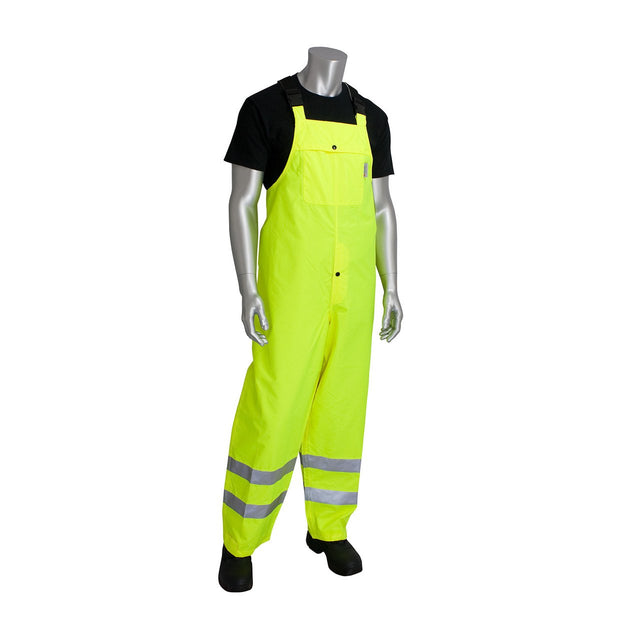 A mannequin is dressed in the PIP VizPLUS Waterproof Breathable Bib 353-2001, highlighting the high-visibility clothing with its reflective material at the bottom. The ensemble stands on a white background, showcasing PIP's durable workwear that blends safety with style.