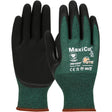 A pair of PIP MaxiCut Oil Seamless Knit Gloves, featuring green and black cut-resistant material with the 'MaxiCut' branding on the back. White text and safety symbols are printed above the wrist area, and the textured nitrile coating enhances grip.