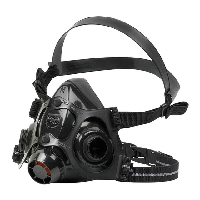The PIP North 7700 Series Silicone Half Mask by PIP is a black industrial respirator made of medical-grade silicone with dual adjustable straps, multiple filter attachment points, a clear faceplate, and a circular front filter for protection against airborne contaminants.