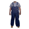 A person wearing a gray t-shirt and GRIT FR Insulated Bib Overalls by GRIT FR Workwear stands facing forward. The modacrylic insulated overalls, made from FR cotton duck canvas with adjustable straps and a front pocket, pair perfectly with brown work boots against the plain white background.