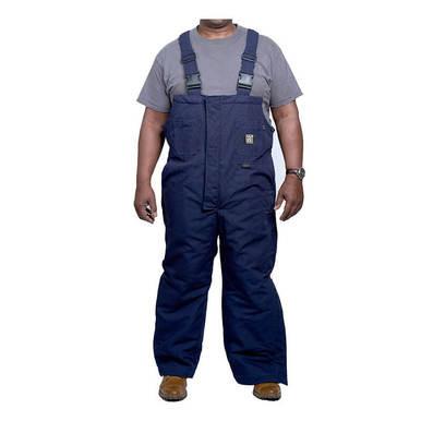 A person wearing a gray t-shirt and GRIT FR Insulated Bib Overalls by GRIT FR Workwear stands facing forward. The modacrylic insulated overalls, made from FR cotton duck canvas with adjustable straps and a front pocket, pair perfectly with brown work boots against the plain white background.