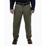 A person wearing GRIT FR Carpenter Pants in Green Duck from GRIT FR Workwear, paired with a black belt, a dark long-sleeve shirt, and brown shoes, stands against a plain white background, showcasing a classic work wear style.