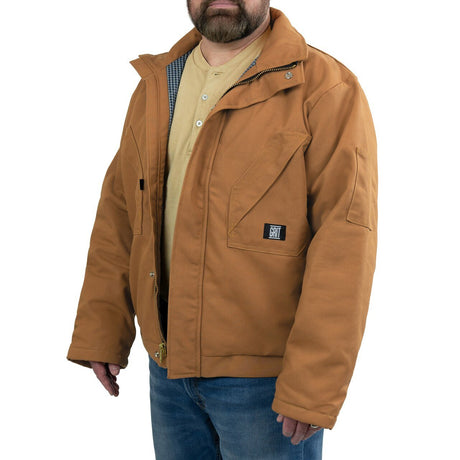 A person wearing a GRIT FR Workwear 13 oz. Insulated Field Jacket with multiple pockets and blue jeans. The jacket, made from FR cotton duck canvas, is unzipped to reveal a light-colored shirt underneath. The background is plain white.