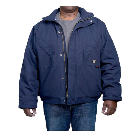 A person is wearing a GRIT FR Insulated Field Jacket from GRIT FR Workwear, which features quilt-lined insulation over a gray shirt and blue jeans. The navy jacket, crafted from flame-resistant cotton duck canvas, includes a front zipper and buttons along with two large chest pockets. Their arms are relaxed by their sides against the white background.