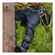 Wearing NSA’s DRIFIRE Slim Straight Leg FR Jean PNT-JSS01 along with other safety gear and climbing equipment, a person scales a wooden utility pole surrounded by greenery in the background.