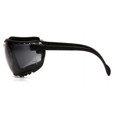 Side view of the Pyramex V2G Goggles GB18_0ST, featuring a black design with tinted lenses and a curved frame. Crafted for safety, these Pyramex Safety goggles provide UV protection and wrap-around coverage to ensure comprehensive eye protection.