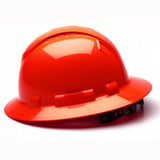 A vibrant Pyramex Ridgeline Vented Full Brim Hard Hat from Pyramex Safety, featuring a glossy red finish, rests on a white surface showcasing its side profile. The helmet includes a wide brim, adjustable straps underneath, and ratchet suspension for enhanced comfort.