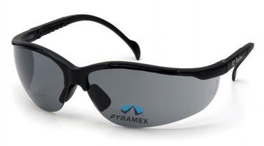 The Pyramex Venture II V2 Reader Safety Glasses feature a sleek design with black frames and tinted lenses. The "PYRAMEX" logo is displayed on one lens. These bifocal glasses, compliant with OSHA ANSI Z87.1 standards, provide maximum protection for users.